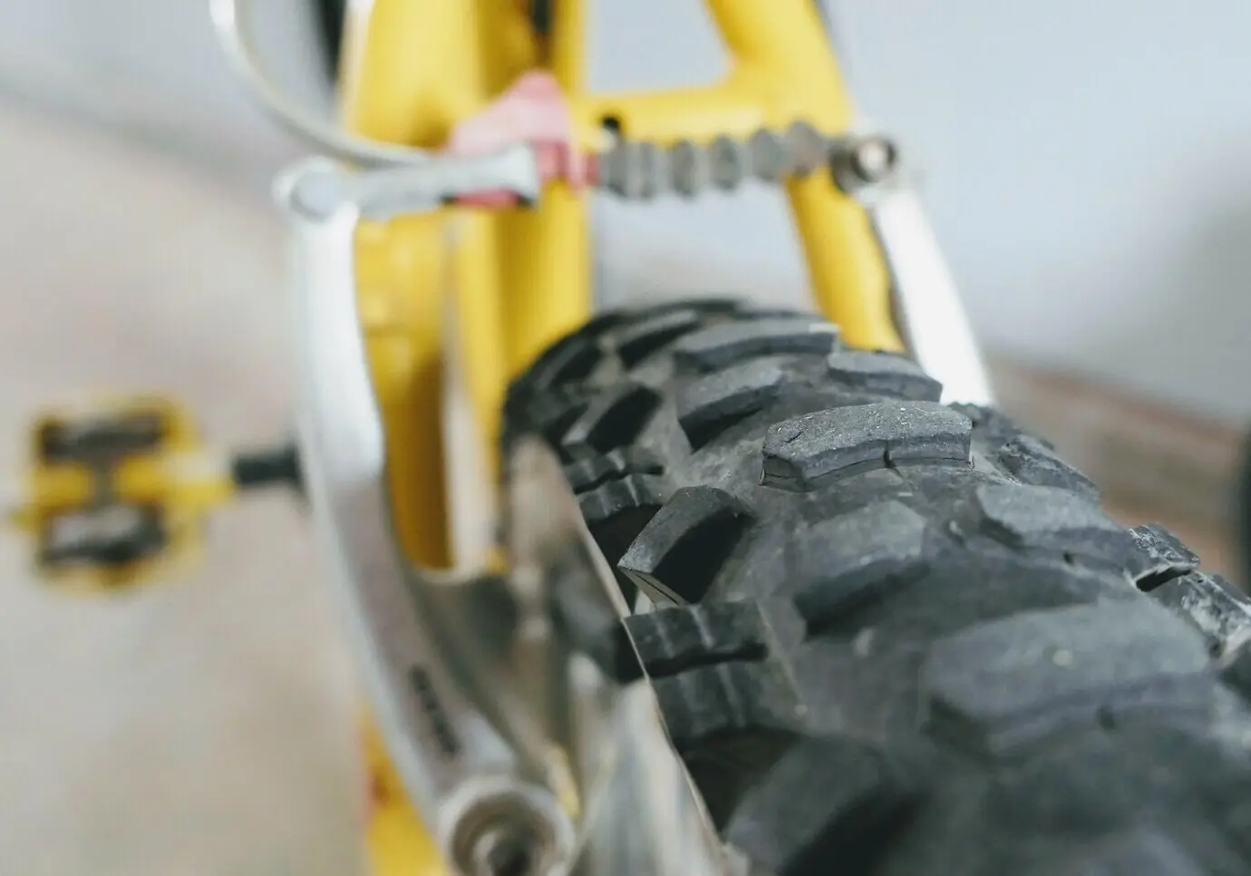 La bande de roulement d’un pneu de VTT jaune, avec des freins en arrière-plan.